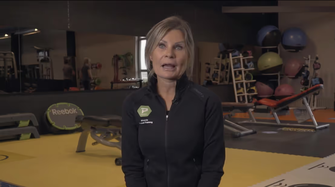 Mujer con chaqueta negra de Reebok en el gimnasio con material de fitness