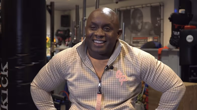 Hombre sonriente con chaqueta de cuadros en el gimnasio con expresión alegre