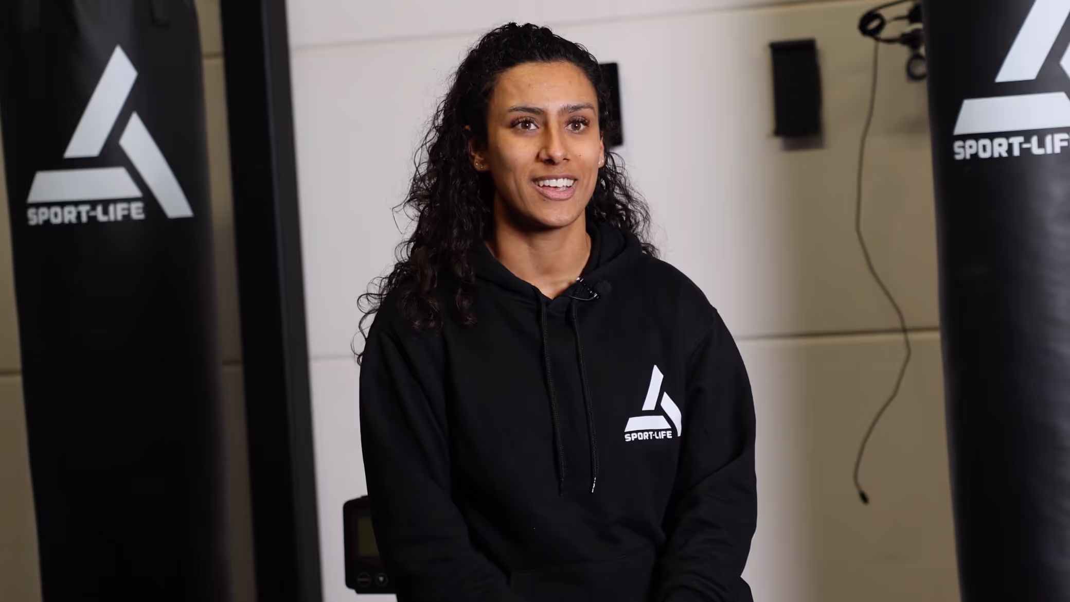 Deportista sonriente con sudadera negra de Sport-Life en la zona de entrenamiento