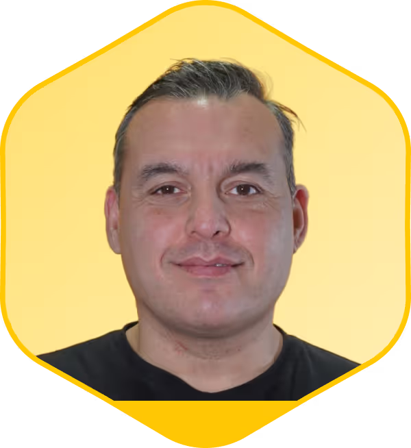 Retrato de un hombre con camiseta negra sobre un fondo hexagonal amarillo